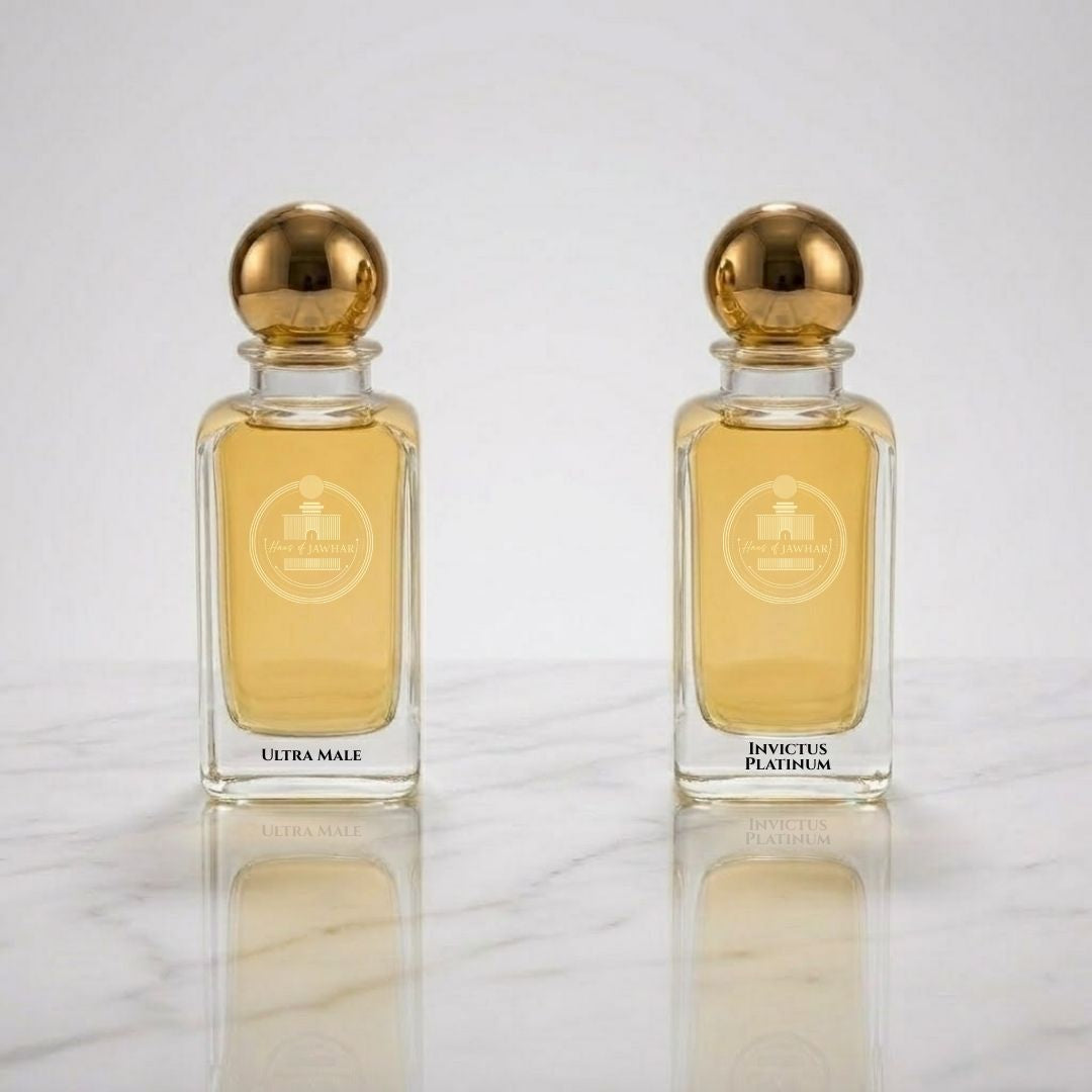 Two perfume bottles with gold caps on a reflective surface.